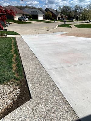 Residential driveway with freshly poured concrete and landscaped edges on a sunny day.