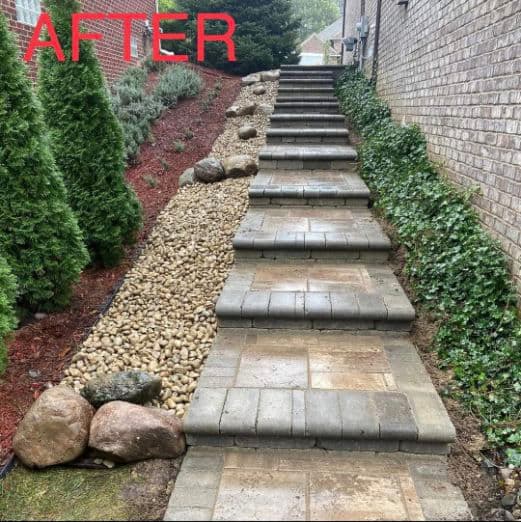 Updated stone pathway with landscaping, decorative rocks, and greenery on either side.