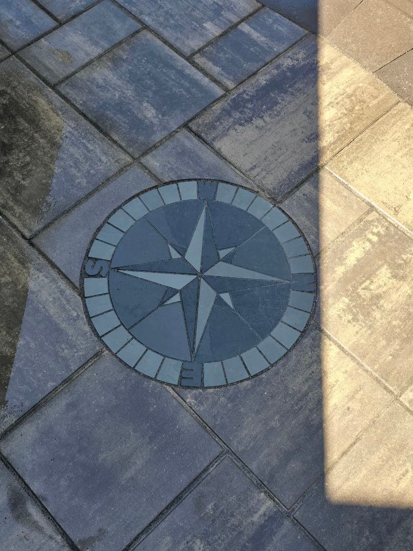 Compass rose design in stone pavement with directional markings and a circular layout.