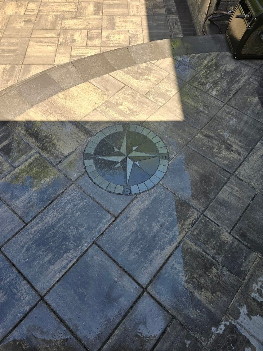 Compass design in stone patio with geometric tile pattern and sunlight reflections.