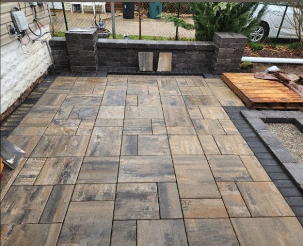 Newly paved outdoor patio with textured stone tiles and stone wall feature.