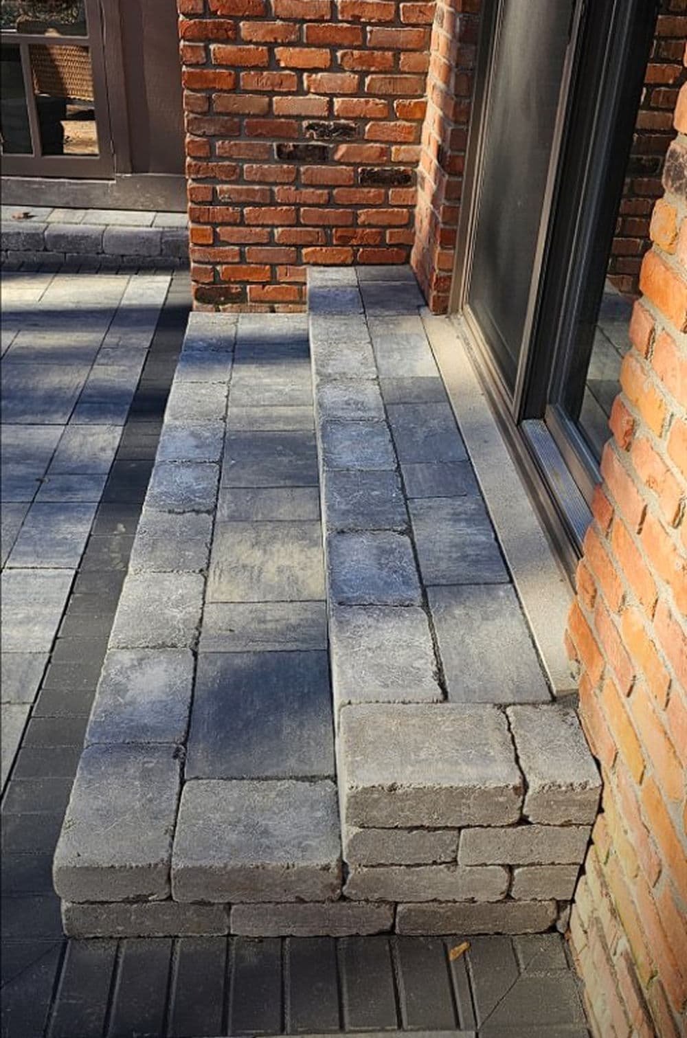 Paved stone steps leading to a brick wall in a modern outdoor setting.