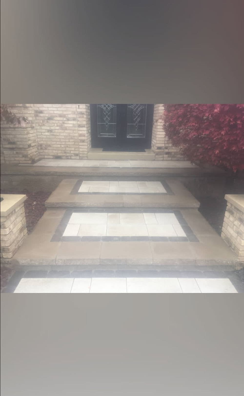 Stylish stone steps leading to a modern front door, framed by decorative landscaping.
