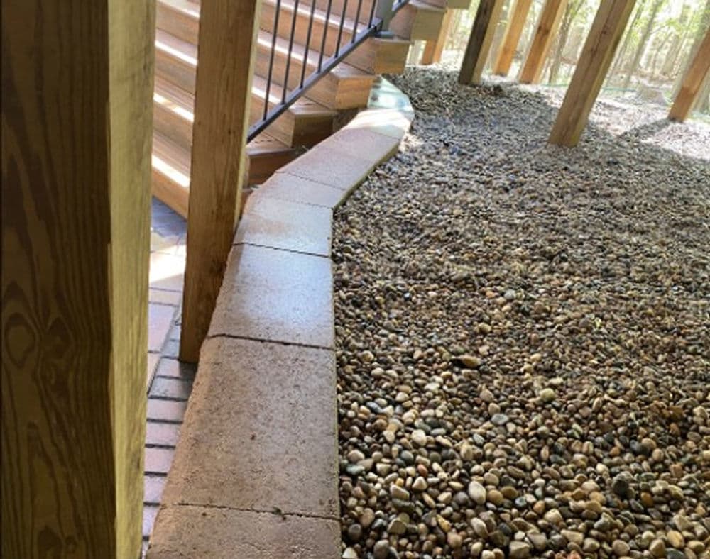 Curved stone pathway alongside wooden stairs in a natural setting.