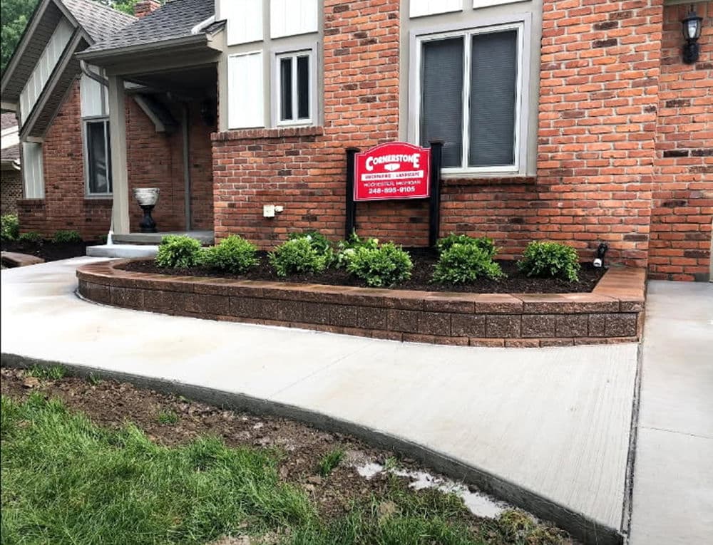 Landscaped front yard with brick edging and sign for Cornerstone Lawn Care services.